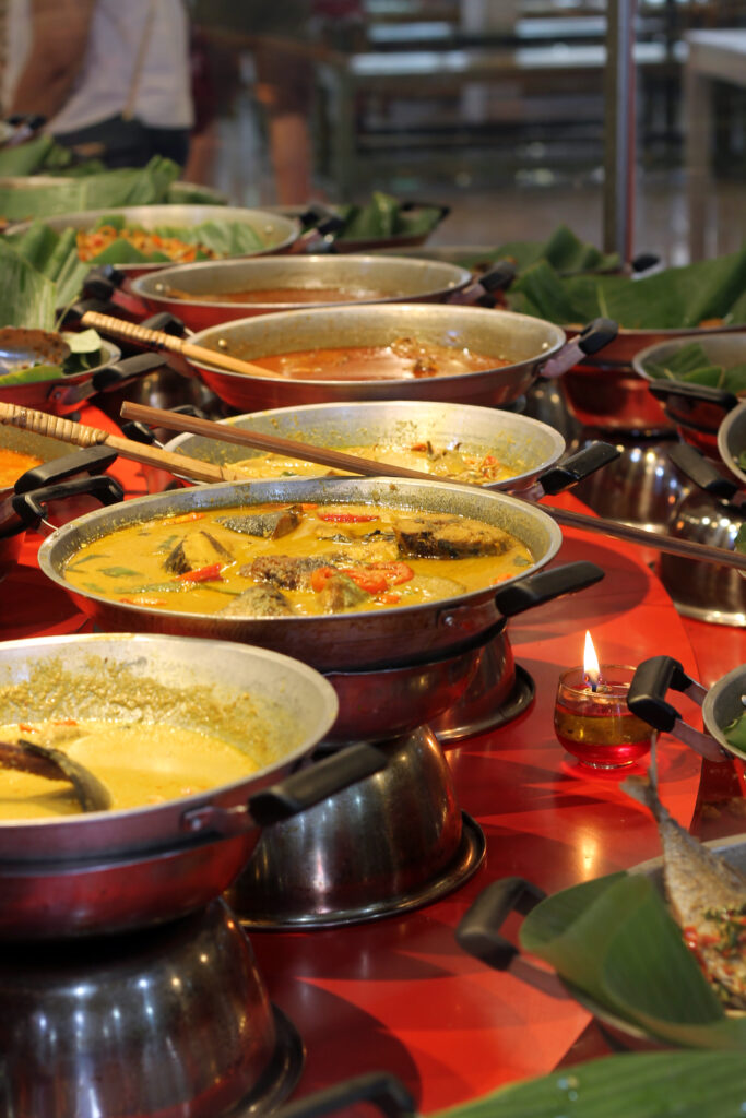 a vibrant buffet of various dishes displayed in a nasi padang or nasi kapau styled restaurant. popular fast food in indonesia. selective focus. an array of curries and stews, a variety of flavorful options that is rich in spices.