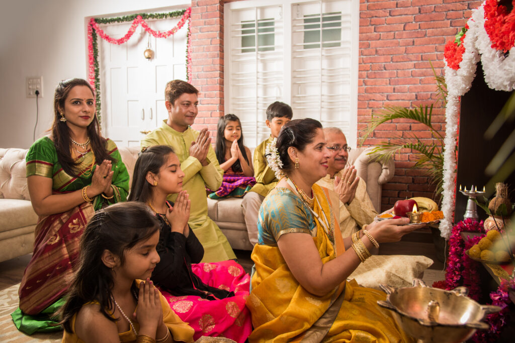 Traditional Event Satisfaction Seen Through a Family’s Eyes indian asian smart family performing ganesh puja or aarti at home while wearing traditional wear